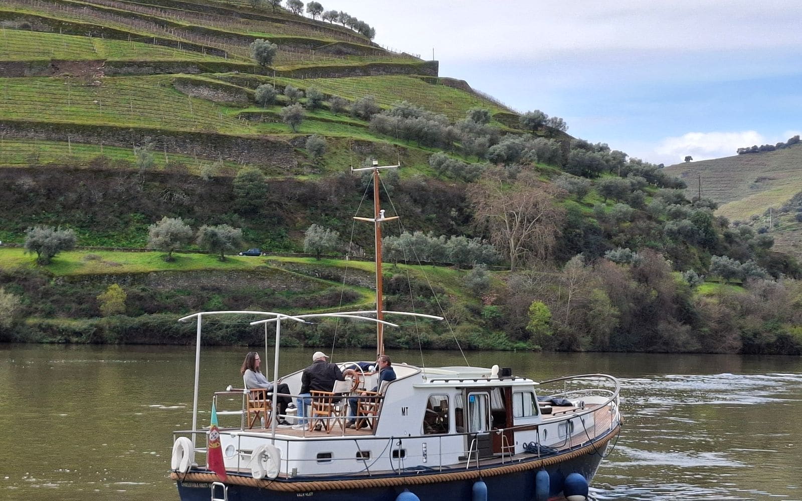 Boat cruising on the Douro River between green vineyard terraces