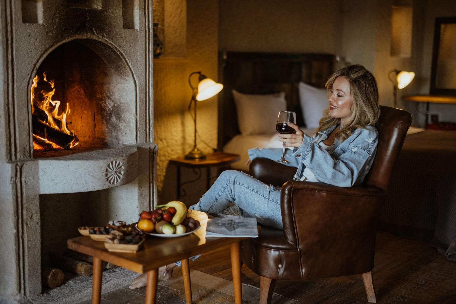 A relaxed hotel stay with wine beside a stone fireplace